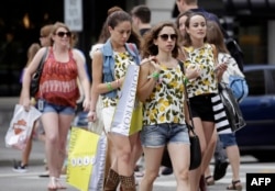 FILE - Consumers hold shopping bags as they walk along Michigan Avenue in Chicago.