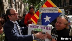 Mayor of Mollerussa Marc Solsona greets a supporter holding a ballot box after testifying at the State Prosecutor's office in Barcelona, Spain, Sept. 19, 2017.