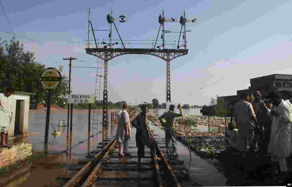 Warga berdiri di jalur kereta yang digenangi banjir setelah hujan lebat di Wazirabad, sekitar 100 kilometer bagian utara Lahore, Pakistan, 7 September 2014.