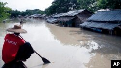 A man paddles his boat near flooded homes in Nyaung Tone, Irrawaddy delta, about 100 kilometers southwest of Yangon, Myanmar, Aug 5, 2015.