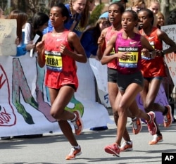 FILE - Buzunesh Deba, left, of Ethiopia, runs in a group of elite female participants past Wellesley College during the 118th Boston Marathon in Wellesley, Mass., April 21, 2014.