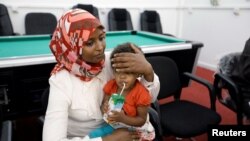 A Sudanese official holds a child of Sudanese Islamic State members who operated in Libya, after Libyan Red Crescent handed them over, in Misrata, Libya August 20, 2017. 