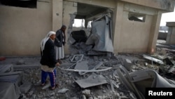 Men inspect the site of an airstrike in Sanaa, Yemen, April 20, 2018. 