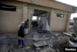 FILE - Men inspect the site of an airstrike in Sanaa, Yemen, April 20, 2018.