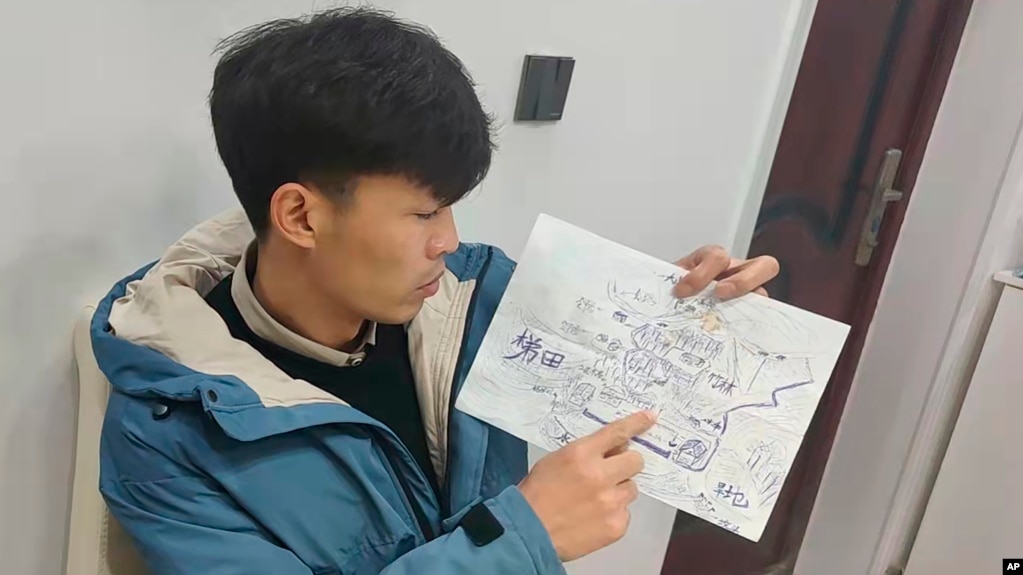 Li Jingwei points to a detail a map he drew from memory of his childhood village as he sits in Lankao in central China's Henan Province, Jan. 5, 2022. Abducted by child traffickers when he was 4 years old, Li was able to find his mother some 30 years later. (Li Jingwei via AP)