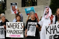 FILE - People hold signs at the Embassy of Saudi Arabia during a protest about the disappearance of Saudi journalist Jamal Khashoggi, Oct. 10, 2018, in Washington.