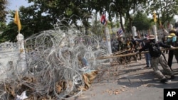 Demo anti-pemerintah memindahkan pagar kawat berduri di kantor PM (yang dikenal dengan sebutan Government House) di Bangkok, Thailand (12/12).
