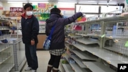 People look for food amid empty shelves in a shop in Fukushima on March 13, 2011.