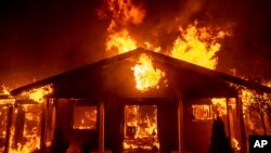 FILE - In this Thursday, Nov. 8, 2018 file photo, a home burns as the Camp Fire rages through Paradise, Calif. (AP Photo/Noah Berger)