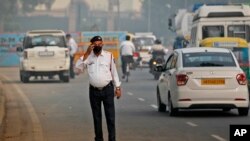 A Delhi Traffic police officer wears a pollution mask and clears the irritants in his eyes in New Delhi, India, Monday, Nov. 4, 2019. (AP Photo/Manish Swarup)
