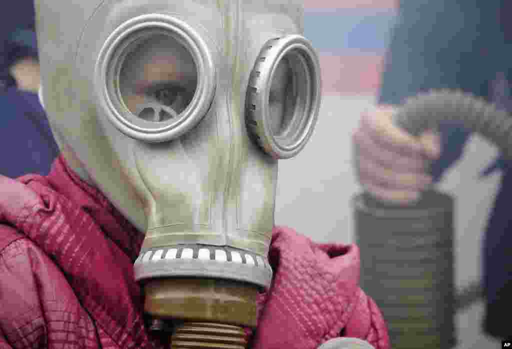 A girl wearing a gas mask exits from a tent full of smoke during a festival marking the 85 th anniversary of civil defense in Russia in St.Petersburg, Oct. 4, 2017.