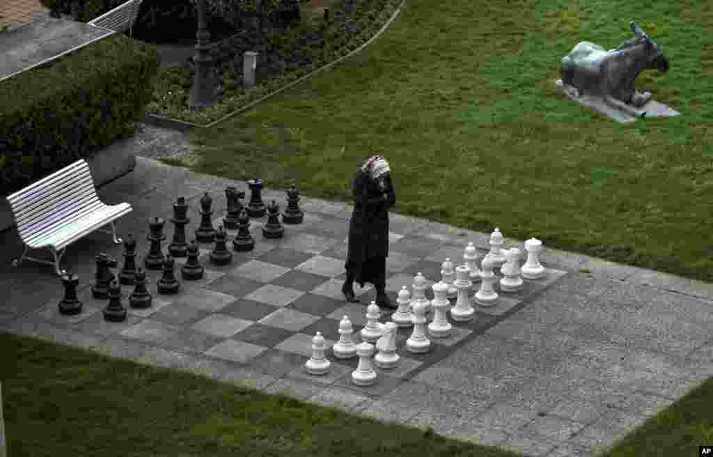 A member of the Iranian media walks on an open air chess board at the site of negotiations about Iran&#39;s nuclear program, between Iran officials and representatives of the world powers in Lausanne, Switzerland.