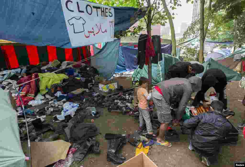 Asylum seekers search for clothes in a makeshift camp outside the foreign office in Brussels, Belgium, Sept. 3, 2015. Some 2,300 people requested asylum in Belgium in June alone, up by a third from May, official figures show. The Belgian government has offered housing for 2,500 extra applicants.
