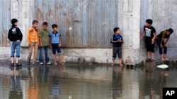 Palestinian children try to cross a waste water - flooded street in Gaza City, Nov. 14, 2013. 