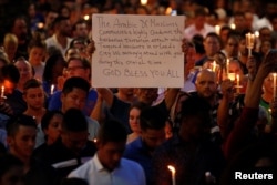 A man holds up a sign saying Arab Muslims condemn the attack as he takes part in a candlelight memorial service after a mass shooting at the Pulse gay nightclub in Orlando, Florida, June 13, 2016.