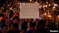 A man holds up a sign saying Arab Muslims condemn the attack as he takes part in a candlelight memorial service after a mass shooting at the Pulse nightclub in Orlando, Florida, June 13, 2016.