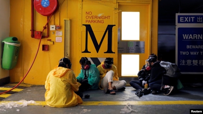 香港理工大学的几名抗议者在地下停车场等候逃走的时机。（2019年11月20日）