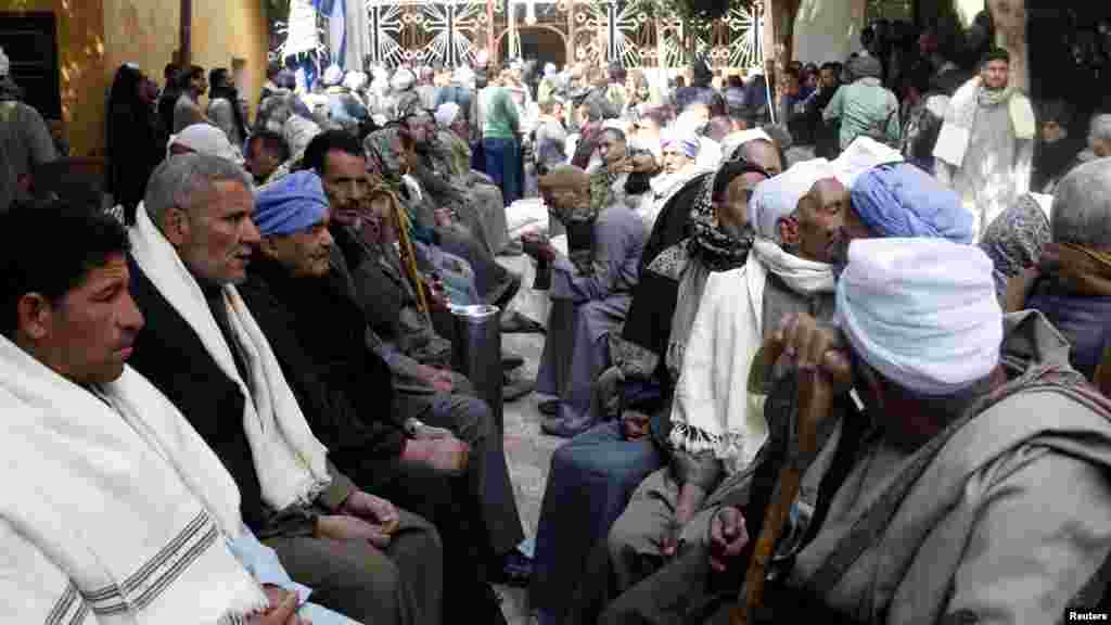 Neighbors and friends of relatives of the Egyptian Coptic men killed in Libya sit at the courtyard of the Virgin Mary Church in the village of el-Aour, near Minya, 220 kilometers (135 miles) south of Cairo, Egypt, Feb. 16, 2015.