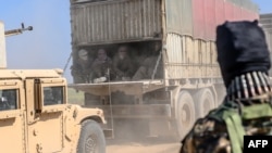 A truck carries men identified as Islamic State group fighters who surrendered to Kurdish-led Syrian Democratic Forces (SDF) as they are transported out of IS's last holdout of Baghuz, Syria, Feb. 20, 2019. 