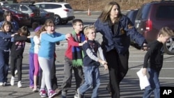 In this photo provided by the Newtown Bee, Connecticut State Police lead children from the Sandy Hook Elementary School in Newtown, Conn., following a reported shooting there, Dec. 14, 2012. 