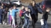 In this photo provided by the Newtown Bee, Connecticut State Police lead children from the Sandy Hook Elementary School in Newtown, Conn., following a reported shooting there, Dec. 14, 2012. 