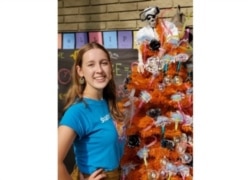 Here, Alina Morse stands next to her creation, a decorated tree for Halloween. (Klint Briney/Zolli Candy via AP)