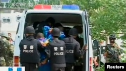 FILE - Riot policemen lead men who are about to be executed into a police van in this still image taken from video in an unknown location in the Xinjiang Uighur Autonomous Region.