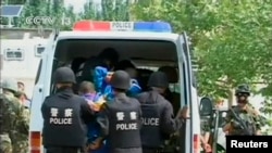 FILE - Riot policemen lead men who are about to be executed into a police van in this still image taken from video in an unknown location in the Xinjiang Uighur Autonomous Region.