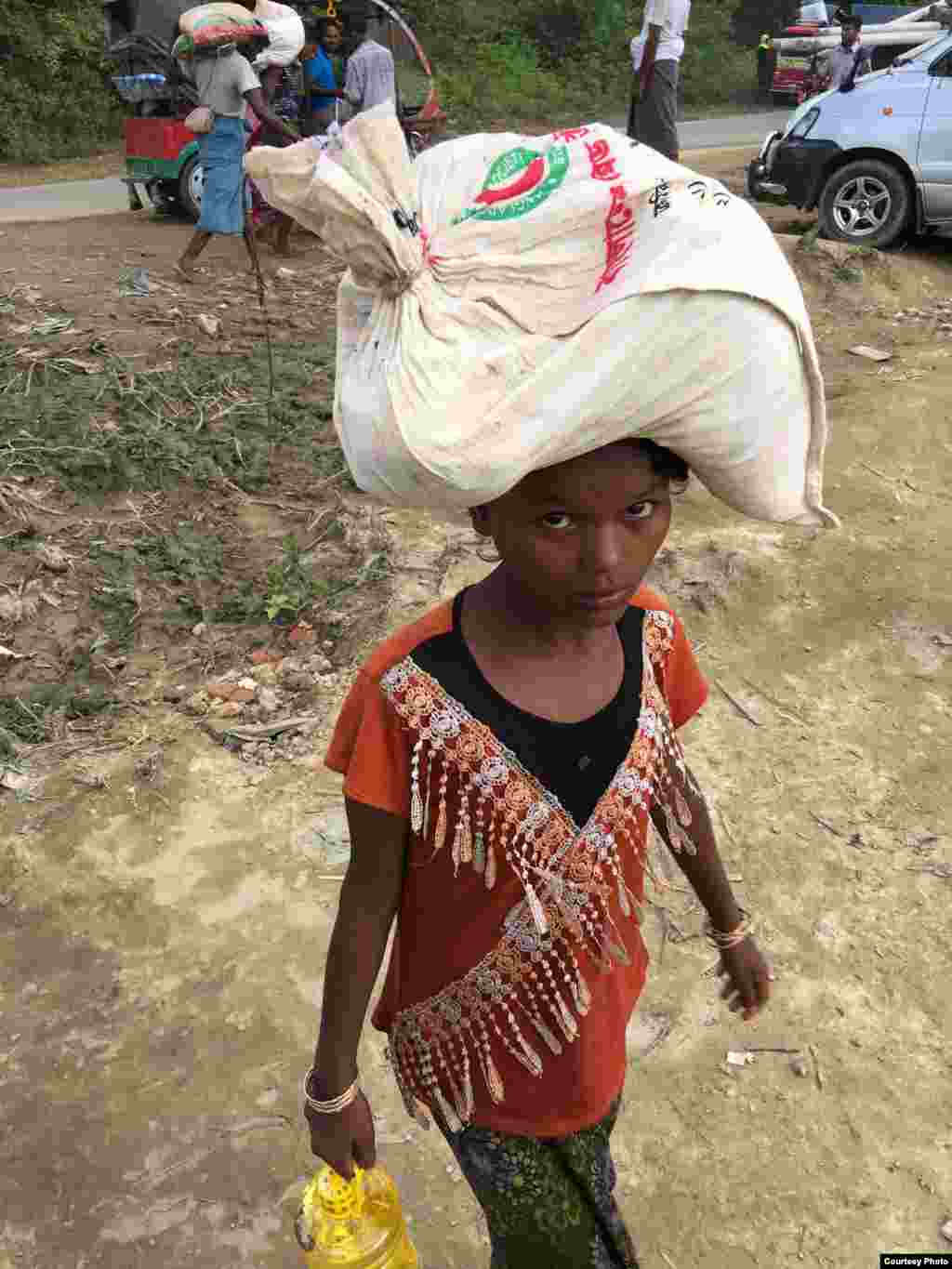 A girl carries supplies on her head at a Rohingya refugee camp in Bangladesh. (Photo courtesy of Dr. Imran Akbar)