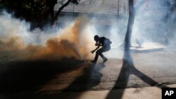 A protester retrieves a tear gas canister from security forces blocking an opposition march from reaching the National Electoral Council headquarters in Caracas, Venezuela, May 24, 2017. 
