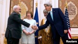U.S. Secretary of State John Kerry (R) and Iranian Foreign Minister Javad Zarif (L) shake hands as Omani Foreign Minister Yussef bin Alawi (2nd R) and EU envoy Catherine Ashton watch in Muscat, Oman, Nov. 9, 2014.