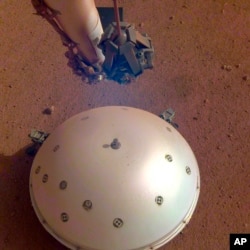 This photo made available by NASA on Tuesday, April 23, 2019 shows the Mars InSight lander's domed wind and thermal shield which covers a seismometer.  (NASA/JPL-Caltech via AP)