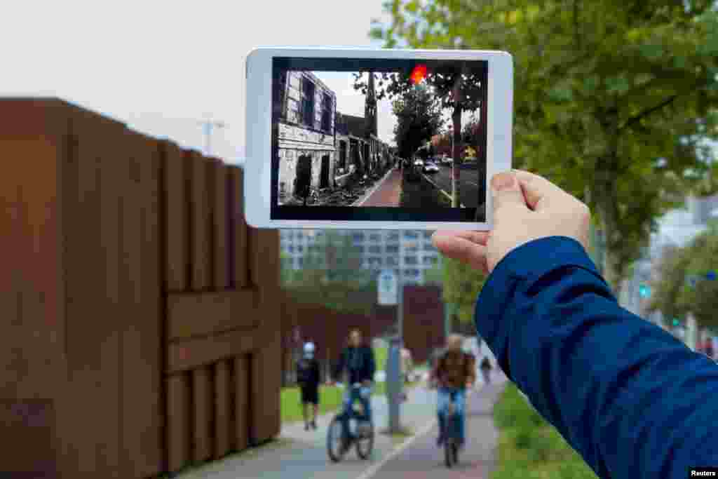 Developer Robin von Hardenberg holds a tablet computer that runs his Timetraveler augmented reality app at Bernauer Street in Berlin. The app superimposes historic footage of scenes that unfolded when the Berlin Wall was erected in 1961 onto today's location when pointing the tablet at the specific spot.