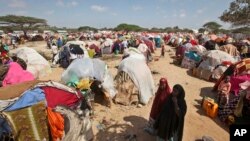 Newly displaced Somalis walk through a camp in the Garasbaley area on the outskirts of Mogadishu, Somalia, March 28, 2017.