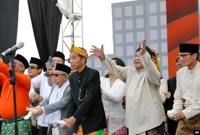 Presiden Joko Widodo (kiri) dan Ma'ruf Amin (kiri) dan capres-cawapres paslon 02, Prabowo Subianto-Sandiaga Uno (kanan) melepas merpati dalam upacara menandai dimulainya kampanye pemilu, 23 September 2018. (Foto: AP/Tatan Syuflana)