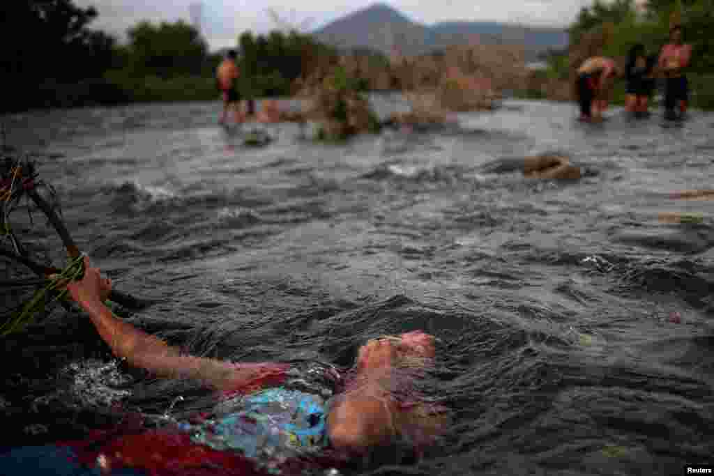 A 14-year-old migrant girl from Honduras baths in a fresh water stream as she and others, part of caravan of thousands from Central America en route to the United States, rest in Pijijiapan, Mexico.