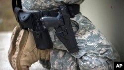 Anggota dari Unit Polisi Militer 139th berlutut dengan senjata tipe Beretta M9 9mm terpasang di pinggangnya dalam latihan penggunaan senjata ringan di Fort Stewart, AS, pada 29 September 2021. (Foto: AP/Stephen B. Morton)