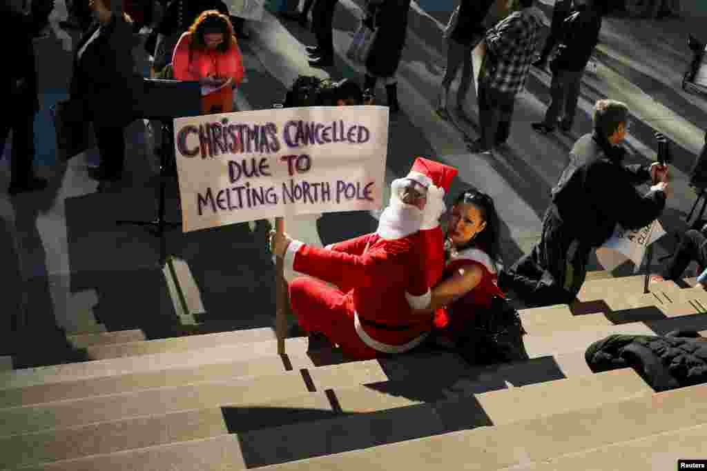 Một người biểu tình ăn mặc như ông già Noel trong một cuộc biểu tình về biến đổi khí hậu trên những bậc thang của Tòa Thị chính Thành phố New York ở quận Manhattan, Thành phố New York, ngày 29 tháng 11 2015, một ngày trước khi bắt đầu Hội nghị Biến đổi Khí hậu Paris (COP21).