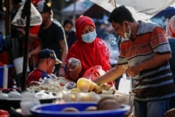 Seorang perempuan mengenakan masker untuk mencegah penularan COVID-19 sedang berbelanja di sebuah pasar tradisional di Jakarta, 1 Maret 2021. (Foto: Willy Kurniawan/Reuters)