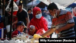Seorang perempuan mengenakan masker untuk mencegah penularan COVID-19 sedang berbelanja di sebuah pasar tradisional di Jakarta, 1 Maret 2021. (Foto: Willy Kurniawan/Reuters) 