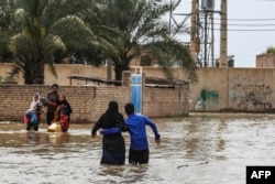 An Iranian family walks through a flooded street in a village around the city of Ahvaz, in Iran's Khuzestan province, on March 31, 2019.