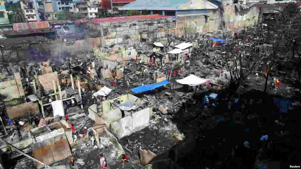 Warga Filipina berusaha mencari barang-barang yang masih bisa dipakai, setelah kebakaran menghanguskan kawasan permukiman kumuh di jalan Tatalon, Quezon, metro Manila.