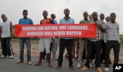 Young men hold a banner on the road that the convoy of the United Nations Security Council delegation took, in Bujumbura, Burundi, Jan. 21, 2016.