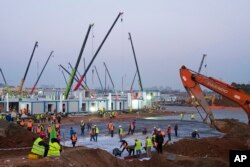 Construction workers labor at the site of the Huoshenshan temporary field hospital being built in Wuhan in central China's Hubei Province, Thursday, Jan. 30, 2020. (AP Photo/Arek Rataj)