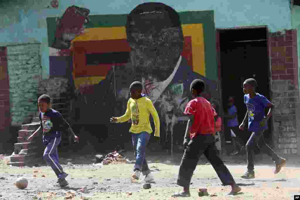Crianças jogam futebol perto de um retrato desfigurado do ex-líder zimbabueano, Robert Mugabe em Harare no dia 6 de setembro 2019. Mugabe, demitiu-se depois um golpe que o obrigou a deixar o poder em 2017