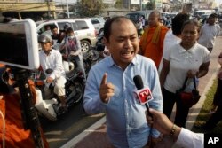 FILE - Political commentator Kim Sok, center, talks to the press as he makes his way joined by his supporters to the municipal court in Phnom Penh, Cambodia.