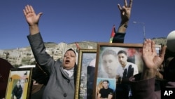 Palestinian women hold pictures of prisoners jailed in Israel during a rally calling for their release, in the West Bank city of Nablus, February 4, 2013.