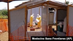 FILE - Health care workers from Medecins Sans Frontieres prepare isolation and treatment areas for their Ebola, hemorrhagic fever operations, in Gueckedou, Guinea. 