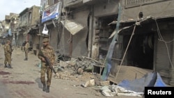 Pasukan keamanan Pakistan memeriksa lokasi ledakan di dekat prosesi kaum Syiah di Dera Ismail Khan hari Minggu (25/11).