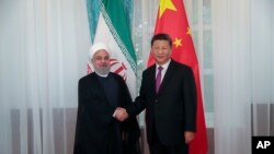 图为伊朗总统鲁哈尼与中国国家主席习近平握手。(2019年6月14日)